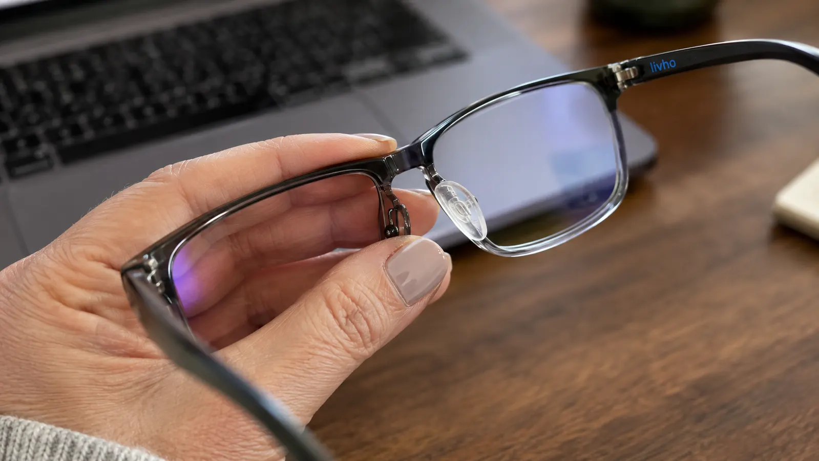 Close up of a thumb pressing on the nose pad of the livho glasses to show wear