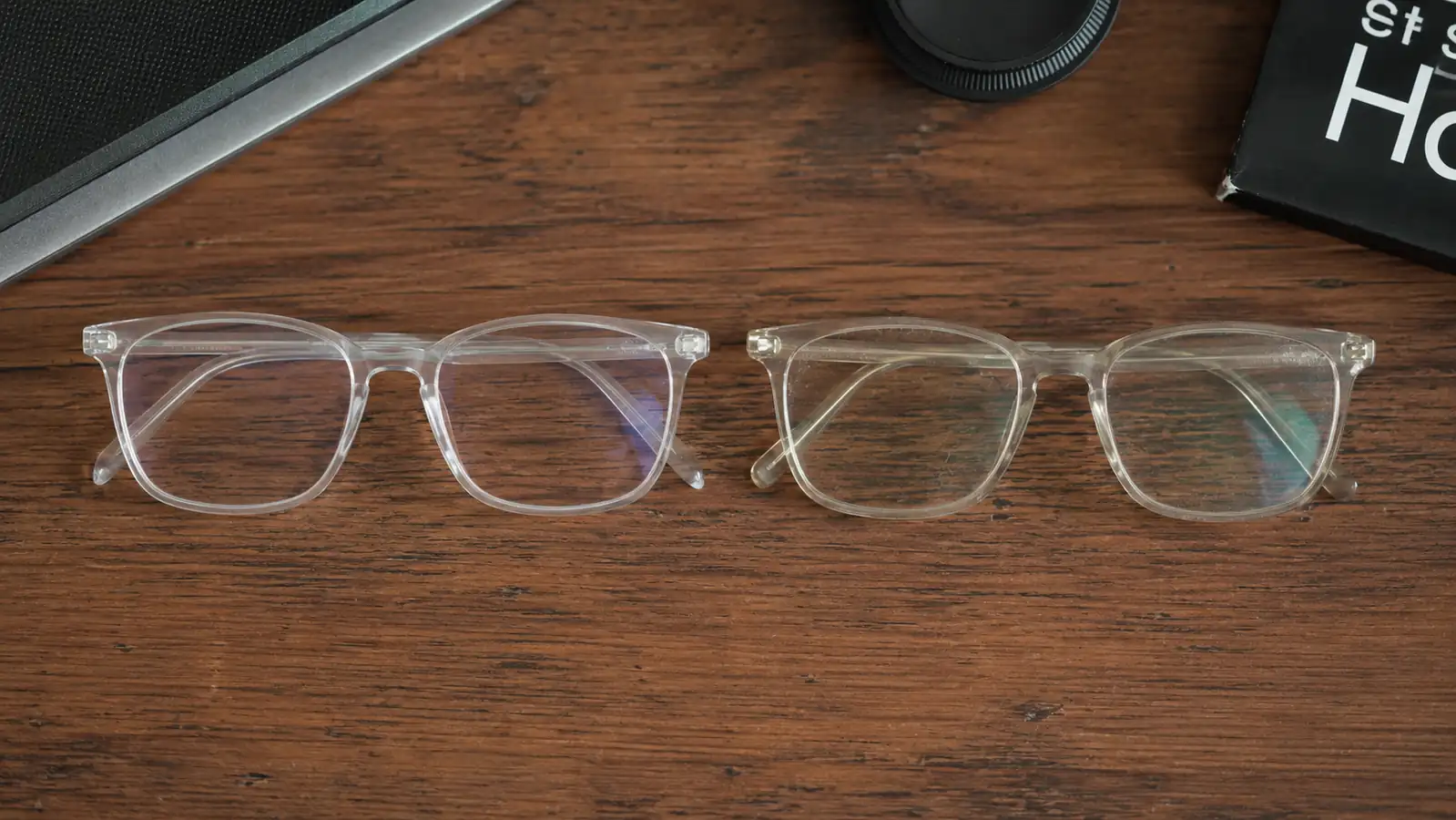 Two pairs of the same livho glasses side by side on a desk, one newer and one visibly older with worn nose pads