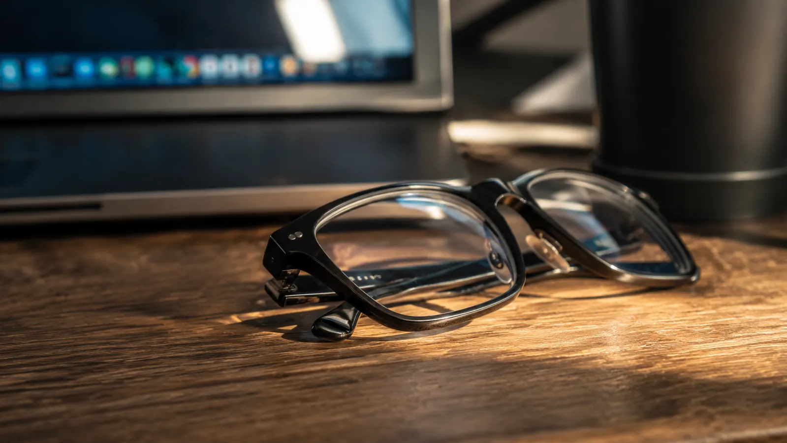 Close up of the livho glasses folded on a desk next to a monitor showing screen glare